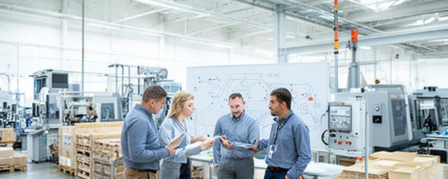 Operations team reviewing material flow and route planning on a bright manufacturing floor